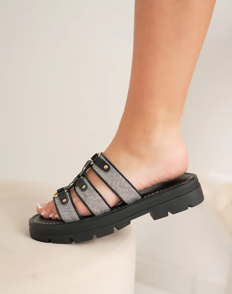 Mules plates femme noires à brides tissées avec bijoux dorés et semelle crantée