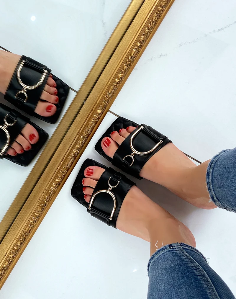 Mules plates noires à détail doré asymétrique
